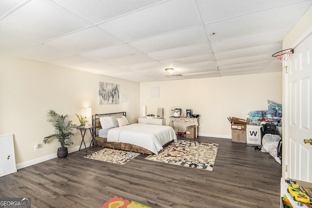 bedroom featuring visible vents, a paneled ceiling, baseboards, and wood finished floors