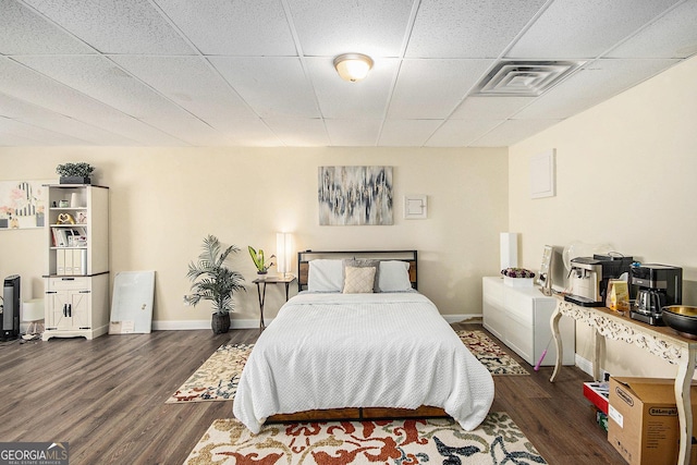 bedroom with visible vents, a paneled ceiling, baseboards, and wood finished floors