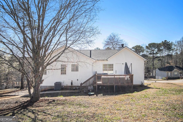 rear view of house featuring cooling unit, a yard, a shingled roof, a chimney, and a deck