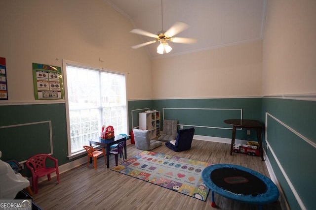 rec room with a wainscoted wall, wood finished floors, a ceiling fan, and ornamental molding