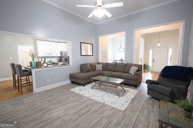 living area with baseboards, a high ceiling, wood finished floors, and crown molding