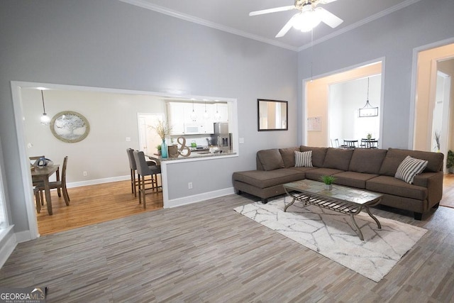 living area featuring baseboards, a high ceiling, wood finished floors, and crown molding