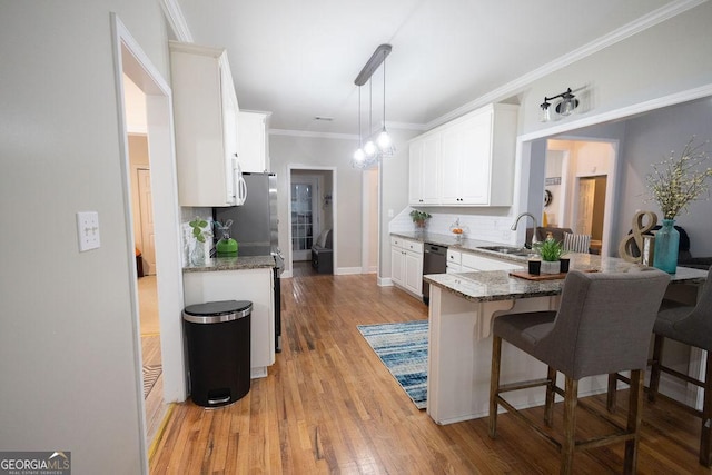 kitchen featuring light stone counters, dishwasher, a kitchen breakfast bar, and a sink