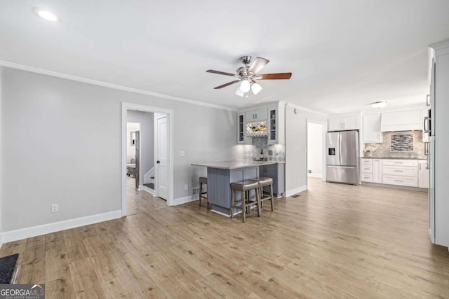 kitchen featuring a peninsula, crown molding, stainless steel fridge with ice dispenser, and backsplash