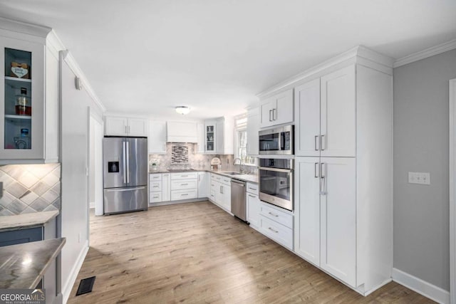 kitchen with visible vents, crown molding, glass insert cabinets, appliances with stainless steel finishes, and a sink