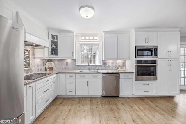 kitchen featuring premium range hood, a sink, white cabinetry, stainless steel appliances, and light wood finished floors