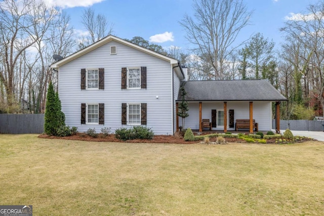 traditional-style house with a porch, a front lawn, and fence