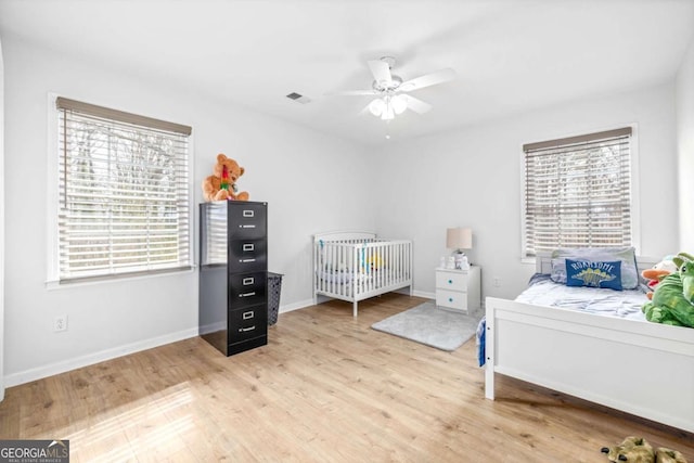 bedroom featuring light wood-type flooring, multiple windows, baseboards, and visible vents