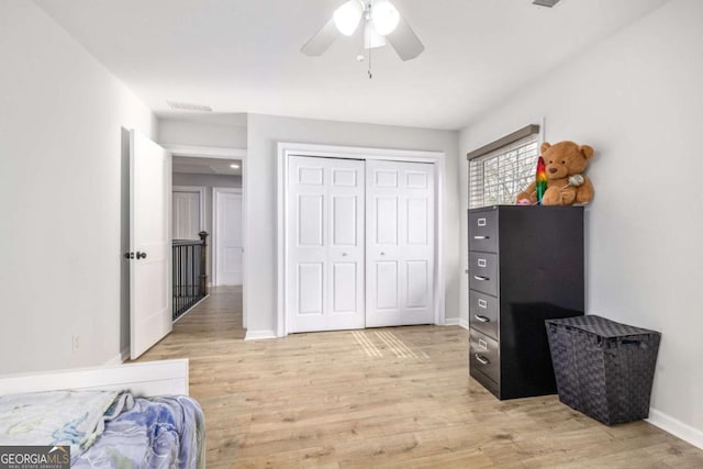 bedroom featuring light wood-style flooring, a ceiling fan, baseboards, and a closet