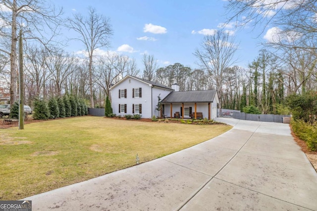 view of front of house with concrete driveway, covered porch, and a front yard