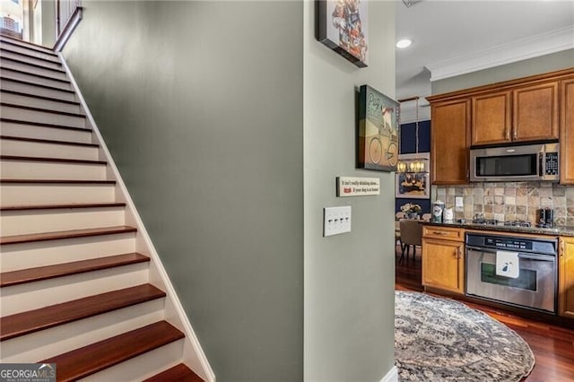 stairway with baseboards, wood finished floors, and crown molding