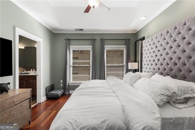 bedroom with visible vents, connected bathroom, baseboards, a tray ceiling, and dark wood-style flooring