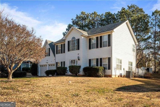 colonial home with an attached garage, central AC, and a front lawn