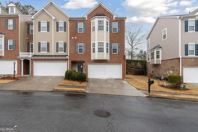 multi unit property featuring a garage, brick siding, and concrete driveway