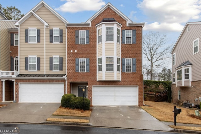 view of property with an attached garage, brick siding, and driveway