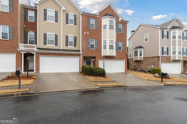 multi unit property with brick siding, driveway, and a garage