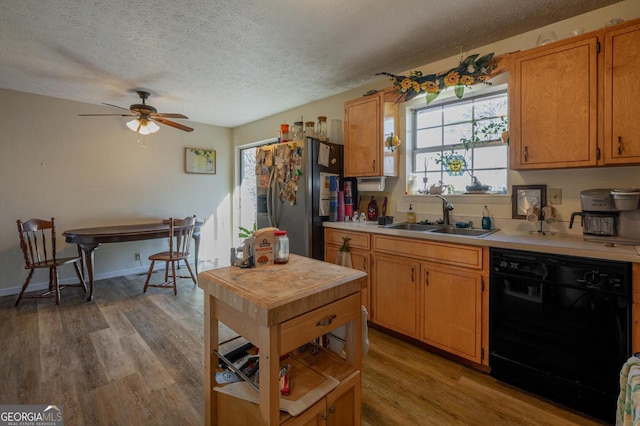 kitchen with light wood finished floors, dishwasher, light countertops, stainless steel refrigerator with ice dispenser, and a sink