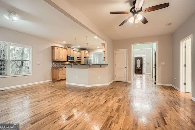 unfurnished living room featuring a ceiling fan, baseboards, and light wood-type flooring