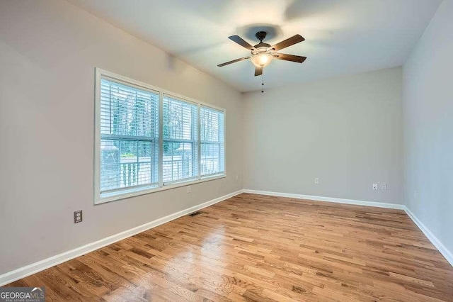 unfurnished room with ceiling fan, visible vents, baseboards, and wood finished floors