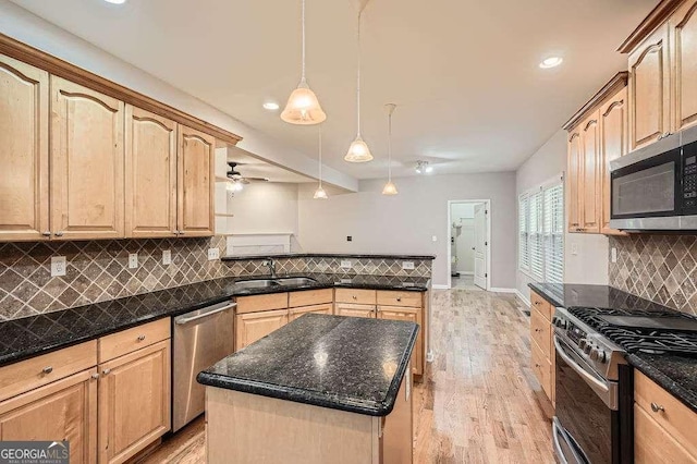 kitchen with light wood-style flooring, light brown cabinets, a sink, stainless steel appliances, and a peninsula