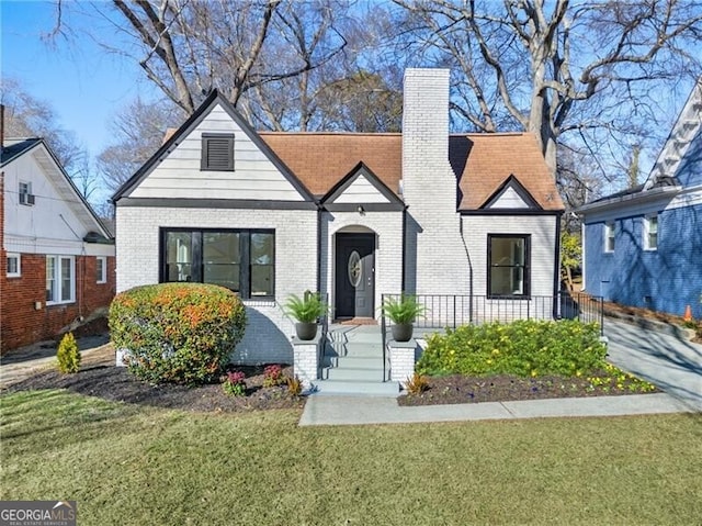 view of front of home featuring brick siding, a chimney, and a front yard