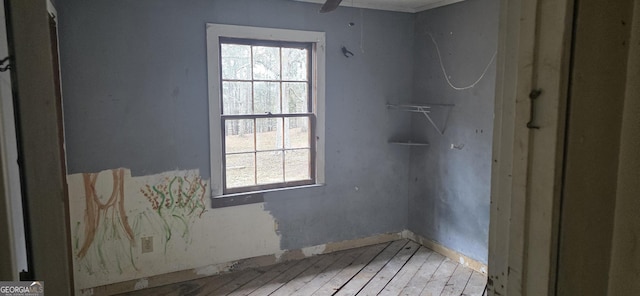 empty room with ceiling fan, a healthy amount of sunlight, and light wood-style flooring