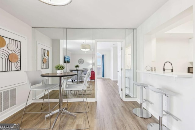 dining space featuring wood finished floors, visible vents, and baseboards