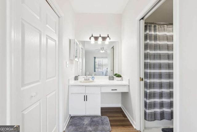 bathroom featuring curtained shower, baseboards, wood finished floors, vanity, and a ceiling fan