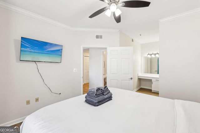 bedroom featuring visible vents, built in study area, wood finished floors, and ornamental molding