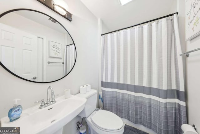 full bath with a sink, curtained shower, toilet, and visible vents