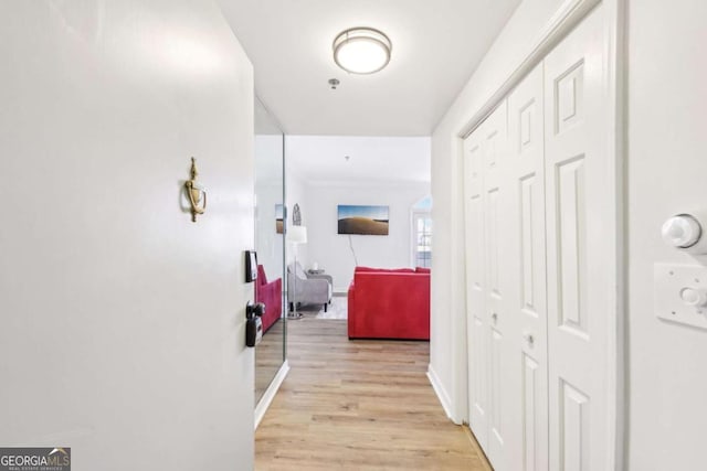 corridor featuring light wood-style flooring and baseboards