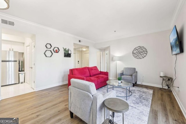 living area featuring visible vents, baseboards, wood finished floors, and crown molding