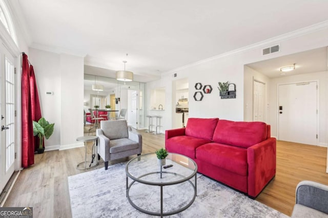 living room with visible vents, ornamental molding, baseboards, and wood finished floors