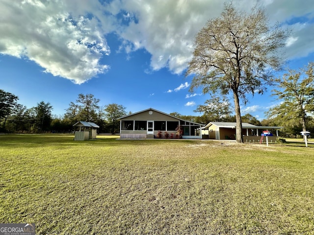 back of house featuring a storage unit, a lawn, an outdoor structure, and a sunroom