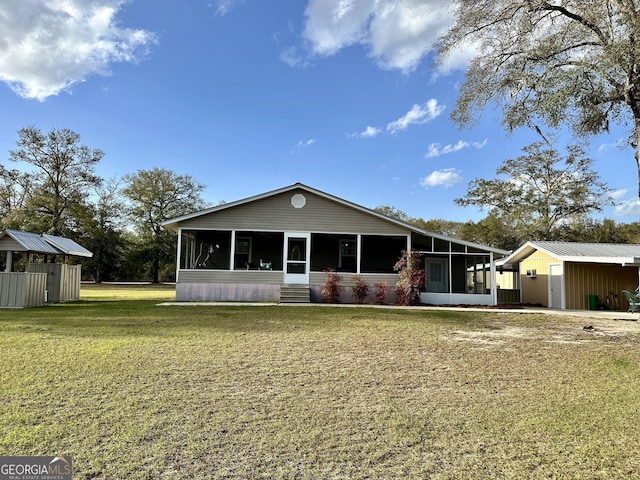 rear view of house featuring an outbuilding, a yard, and a sunroom