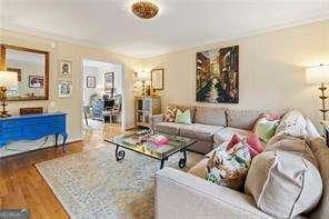 living area with ornamental molding and wood finished floors