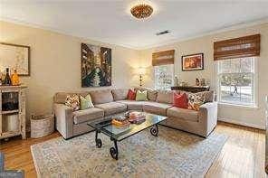 living room featuring plenty of natural light, crown molding, and wood finished floors