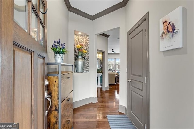 corridor featuring baseboards, wood finished floors, and ornamental molding