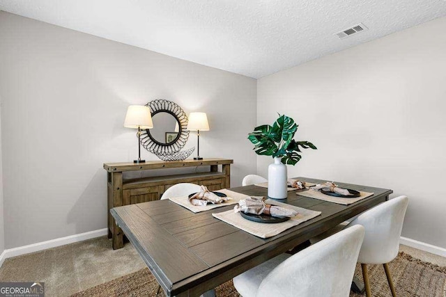 dining area with baseboards, light carpet, a textured ceiling, and visible vents