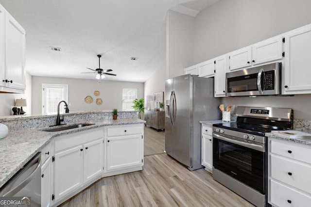 kitchen featuring light wood-style flooring, a sink, light stone counters, white cabinetry, and stainless steel appliances