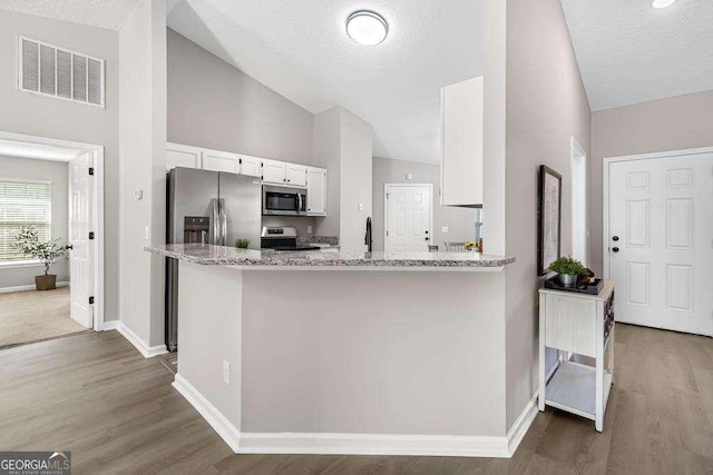 kitchen featuring wood finished floors, light stone countertops, visible vents, appliances with stainless steel finishes, and white cabinetry