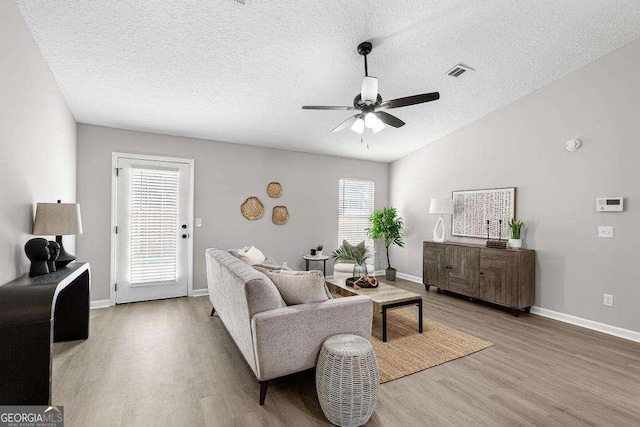 living room with visible vents, a textured ceiling, wood finished floors, lofted ceiling, and ceiling fan