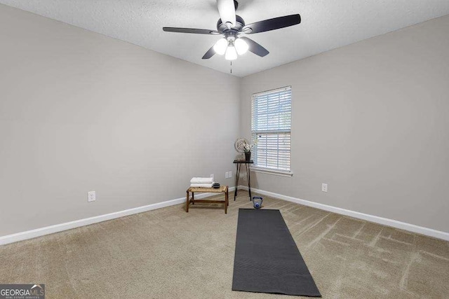 exercise area with a textured ceiling, baseboards, carpet floors, and ceiling fan