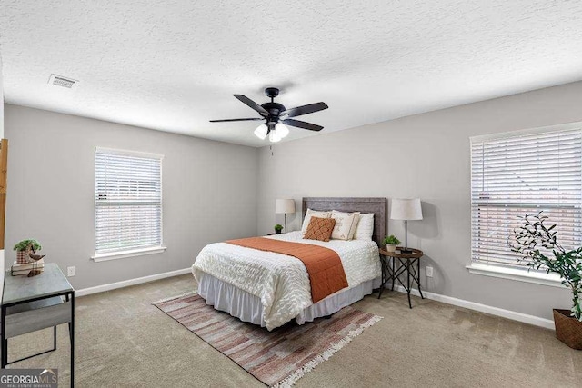 carpeted bedroom with a textured ceiling, visible vents, baseboards, and ceiling fan