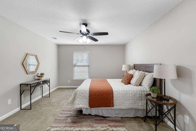 carpeted bedroom with visible vents, a textured ceiling, baseboards, and a ceiling fan