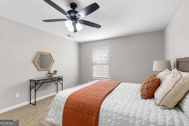 bedroom featuring ceiling fan, a textured ceiling, baseboards, and carpet floors