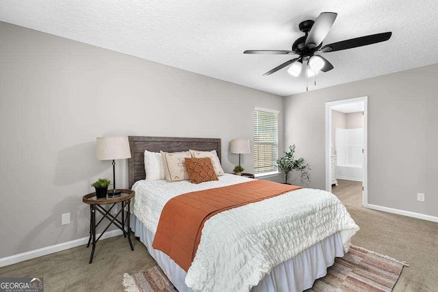 carpeted bedroom featuring baseboards, a textured ceiling, ensuite bath, and a ceiling fan