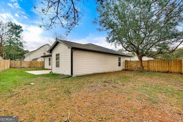 view of side of home with a lawn, a fenced backyard, and a patio area