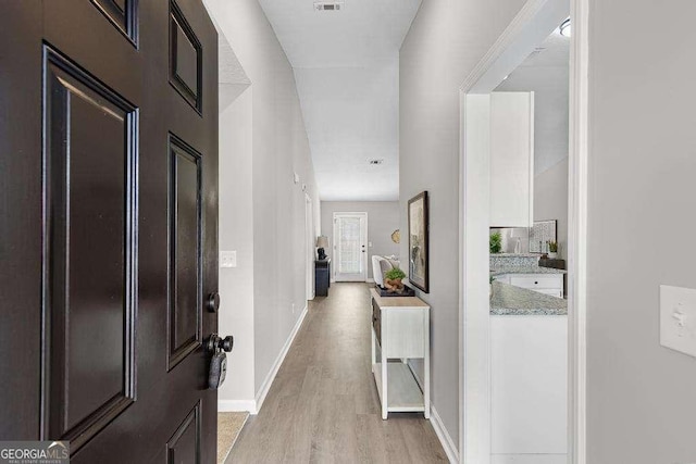 hall featuring visible vents, baseboards, and light wood-style floors