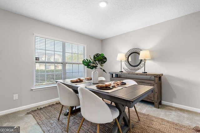 carpeted dining space with baseboards and a textured ceiling